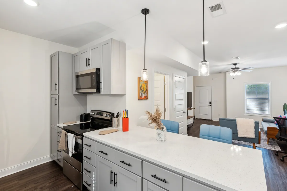 Features a cozy kitchen space with a kitchen island, stainless steel appliances, and a decorative vase, highlighting the modern functionality and inviting atmosphere ideal for cooking meals and entertaining guests.