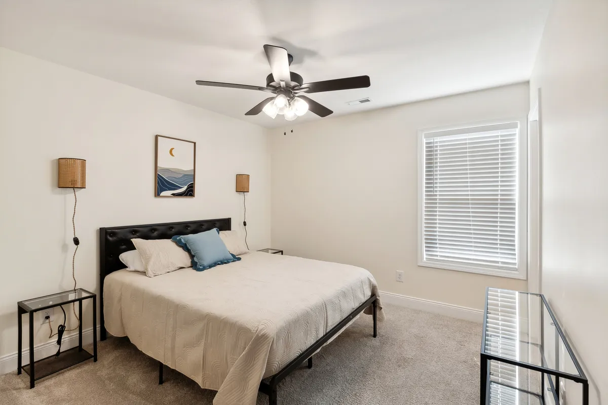 This image showcases a bedroom with a comfortable bed, flanked by nightstands and adorned with calming artwork. Soft natural light streams in through the window, creating a serene retreat ideal for unwinding or reading before sleep.