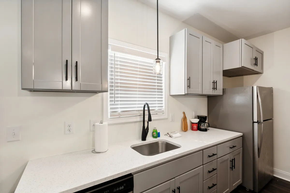 A bright, inviting kitchen setup featuring a clean countertop, modern cabinetry, and a well-lit sink. The arrangement suggests a welcoming space for meal prep or sharing a drink before heading out to explore the city.